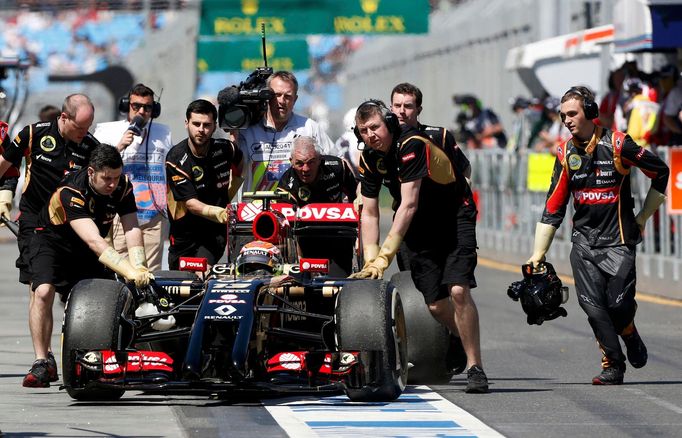 Lotus Formula One driver Pastor Maldonado of Venezuela is being pushed down the pits by mechanics during the first practice session of the Australian F1 Grand Prix at the