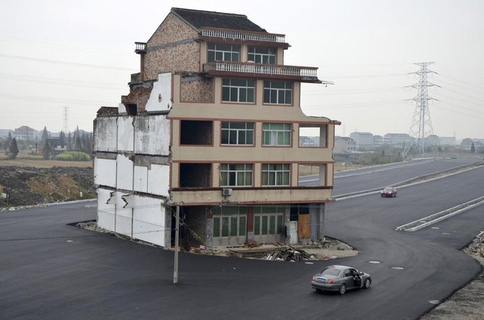 A car stops beside a house in the middle of a newly built road in Wenling, Zhejiang province, November 22, 2012. An elderly couple refused to sign an agreement to allow their house to be demolished. They say that compensation offered is not enough to cover rebuilding costs, according to local media. Their house is the only building left standing on a road which is paved through their village. REUTERS/China Daily (CHINA - Tags: BUSINESS CONSTRUCTION POLITICS SOCIETY TPX IMAGES OF THE DAY) CHINA OUT. NO COMMERCIAL OR EDITORIAL SALES IN CHINA Published: Lis. 22, 2012, 8:36 dop.