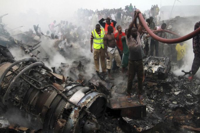 People help rescue workers pull a water hose to extinguish a fire after a plane crashed into a neighbourhood in Ishaga district, an outskirt of Nigeria's commercial capital Lagos June 3, 2012. There were no survivors among the 147 people on board a domestic passenger aircraft that crashed in the Nigerian city of Lagos on Sunday, an official of the National Emergency Management Agency (NEMA), told Reuters. REUTERS/Akintunde Akinleye (NIGERIA - Tags: DISASTER TRANSPORT) Published: Čer. 3, 2012, 8:25 odp.