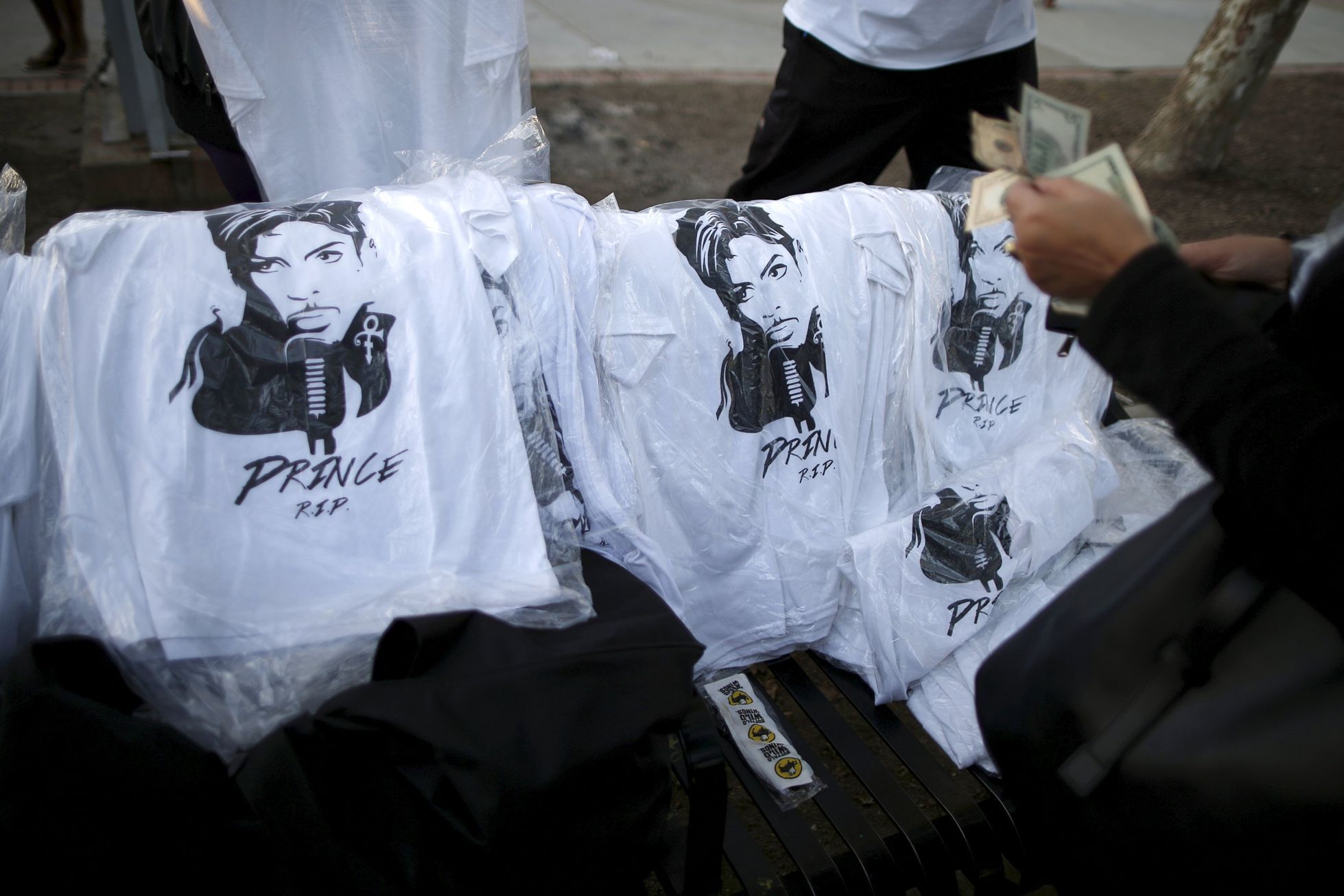 People buy Prince t-shirts at a vigil to celebrate the life and music of deceased musician Prince in Los Angeles