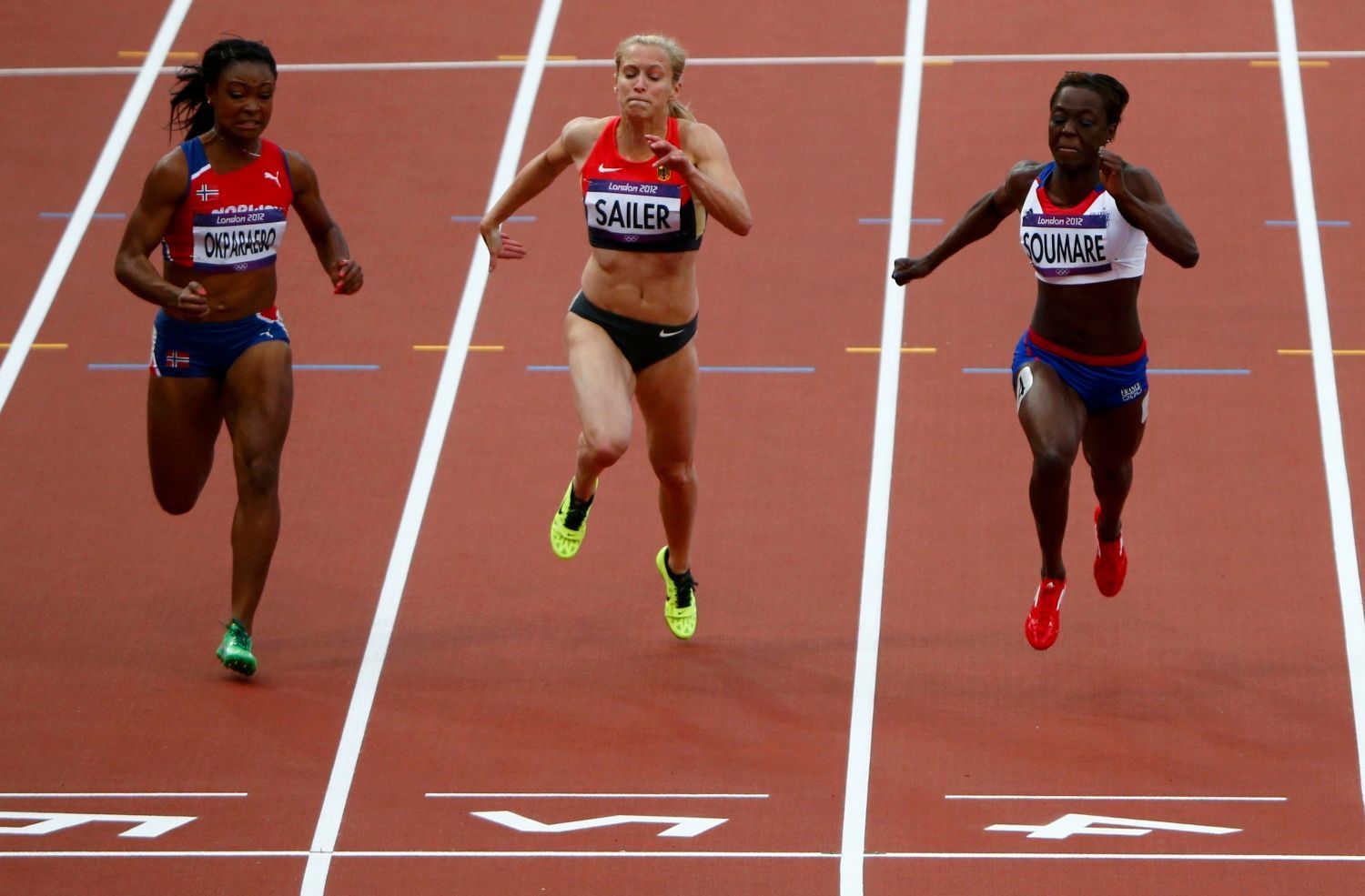 Norská sprinterka Ezinne Okparaebová, Němka Verena Sailerová a Francouzka Myriam Soumareová (zleva) dobíhají závod na 100 metrů v prvním rozběhu OH 2012 v Londýně.