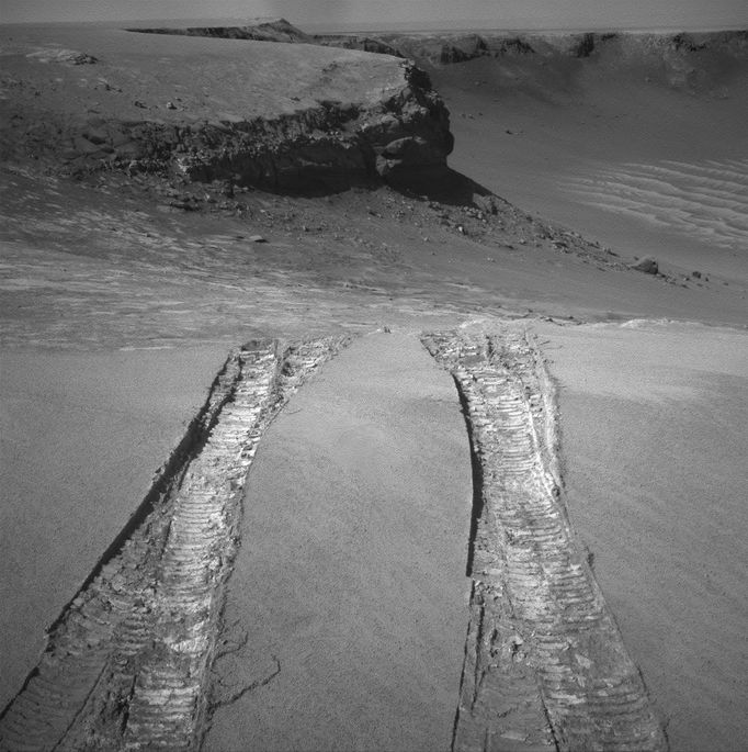 NASA's Mars Exploration Rover Opportunity climbed out of "Victoria Crater" following the tracks it had made when it descended into the 800-meter-diameter (half-mile-diameter) bowl nearly a year earlier. The rover's navigation camera captured this view back into the crater just after finishing a 6.8-meter (22-foot) drive that brought Opportunity out onto level ground during the mission's 1,634th Martian day, or sol (Aug. 28, 2008). The rover laid down the first tracks at this entry and exit point during its 1,291st sol (Sept. 11, 2007), after about a year of exploring around the outside of Victoria Crater for the best access route to the interior. On that sol, Opportunity drove a short distance into the crater and then backed out to check that the footing was good enough to trust this point as an exit route when the work in the crater was finished. Two sols later, Opportunity drove in again for its extended investigation of the rock layers exposed inside the crater. While inside, the rover spent several months using the contact instruments on its robotic arm to analyze the composition of the rock layers it could drive across on the surface of the upper slope. Then Opportunity drove close to the base of the "Cape Verde" promontory that forms part of the crater rim and appears in the upper center of this image. From that perspective, the rover used its panoramic camera to examine details of layering in the 6-meter-tall (20-foot-tall) cliff. For scale, the distance between the parallel tracks left by the rover's wheels is about 1 meter (39 inches) from the middle of one track to the middle of the other. After getting past the top of the inner slope of the crater, the Sol 1634 drive also got through a sand ripple where the tracks appear deepest. Image Credit: NASA/JPL-Caltech