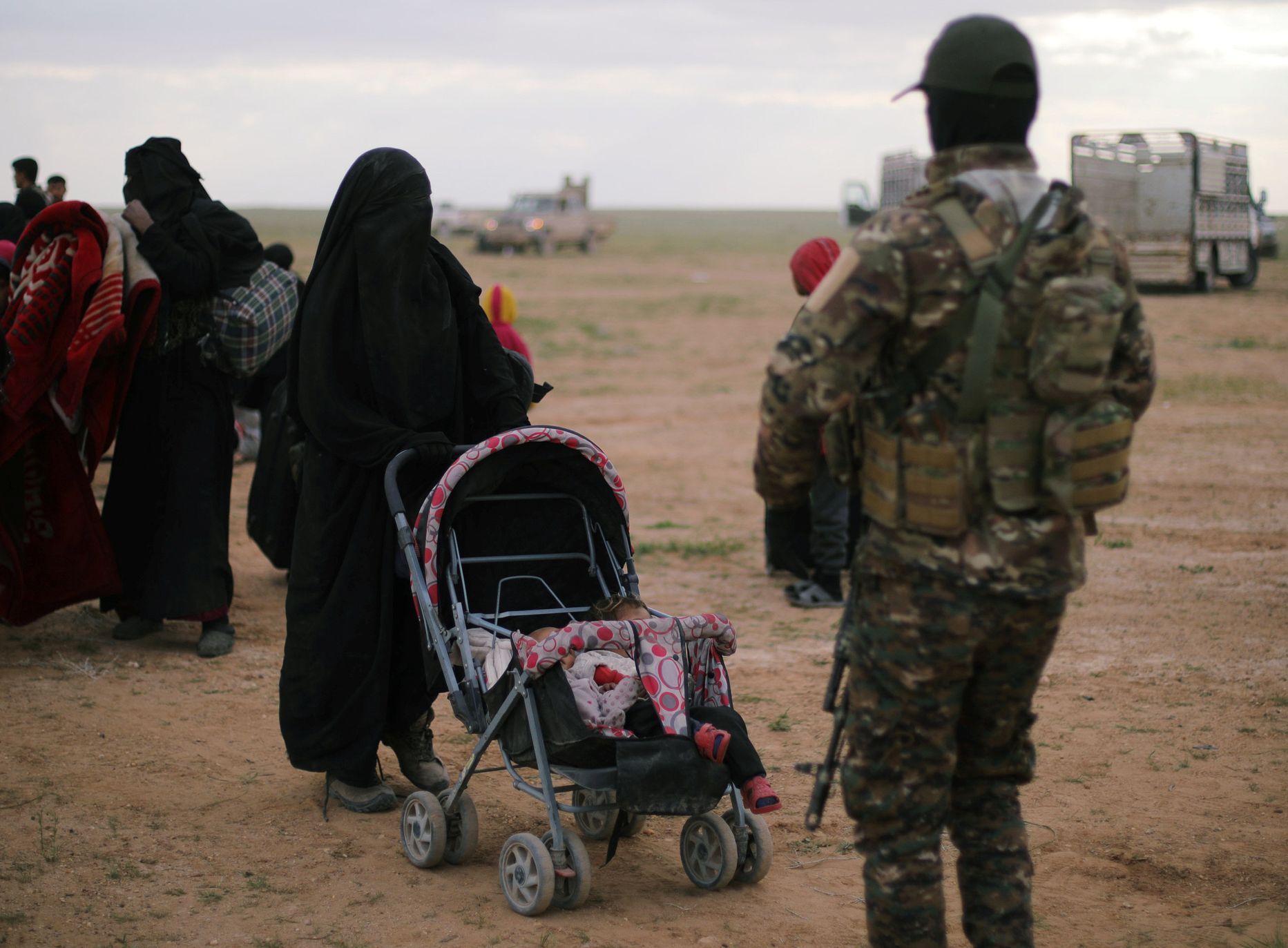 Voják Syrských demokratických sil (SDF) kontroluje ženy, které odešly z vesnice Baghúz. Poslední, kterou stále drží Islámský stát.