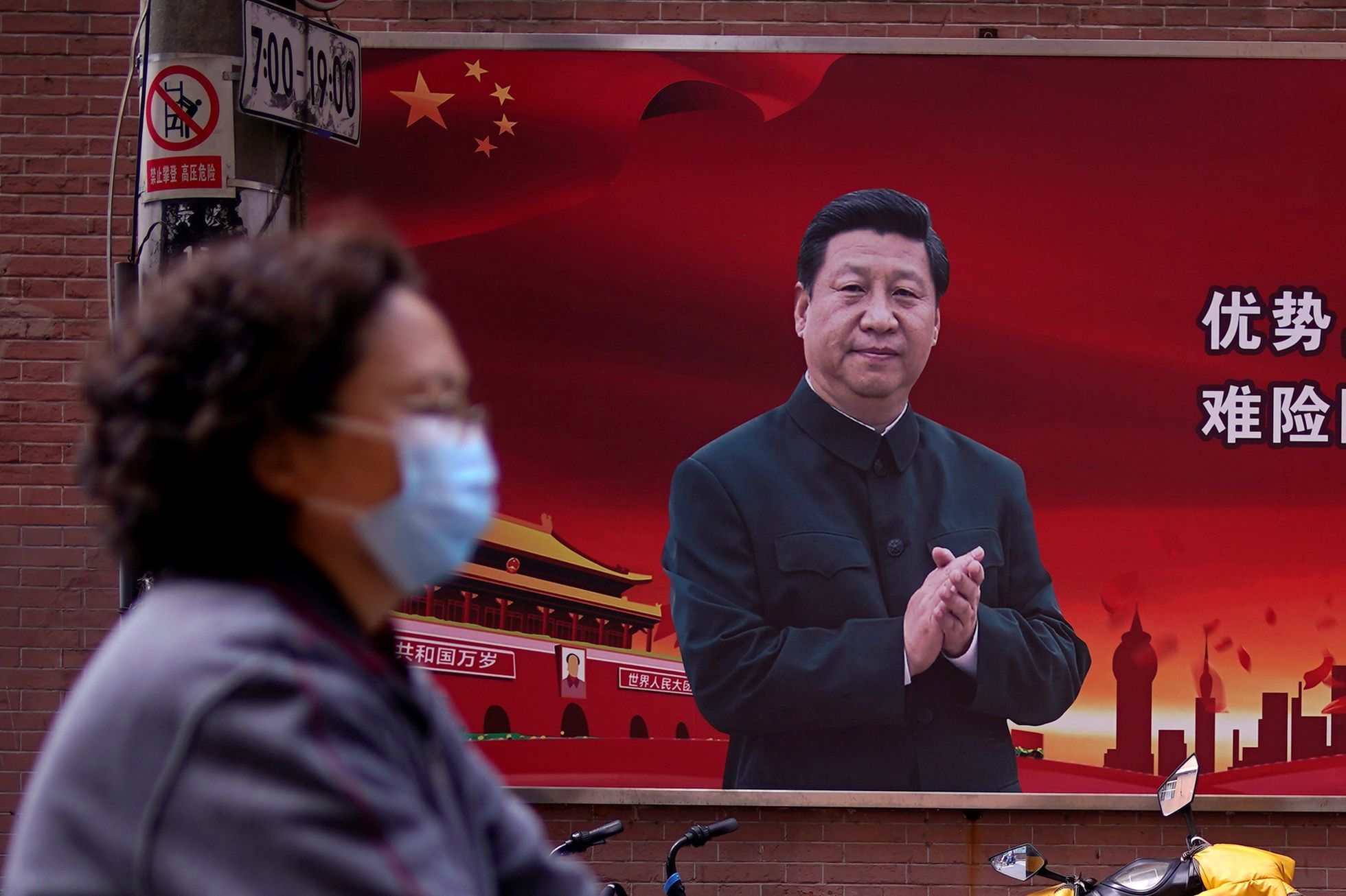 Žena projíždí kolem obřího billboardu s prezidentem Si Ťin-pchingem v Šanghaji.