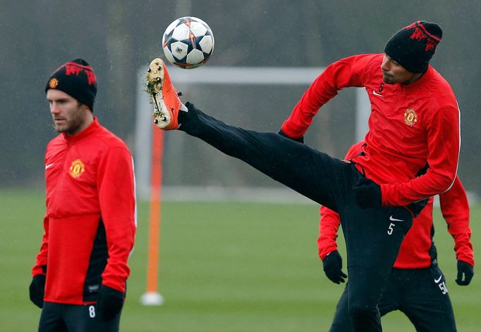 Manchester United's Ferdinand jumps for a ball as Mata looks on during a training session at the club's Carrington training complex in Manchester