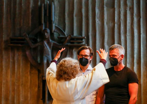 Zaměstnankyně katolického kostela v Kolíně nad Rýnem Brigitte Schmidtová uděluje požehnání Ralfu-Michaelu Bergerovi and Andreasi Helfrichovi, 10. května 2021.