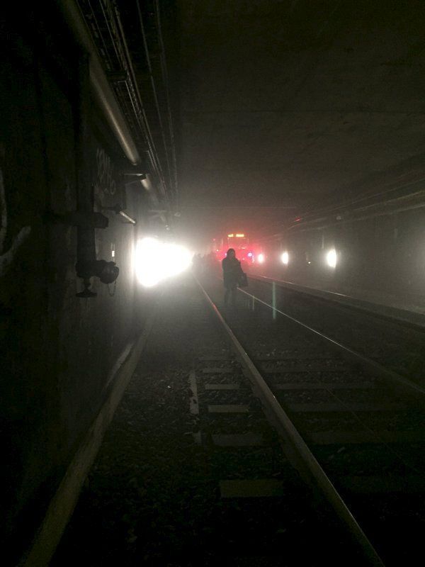 Passengers walk on underground metro tracks to be evacuated after an explosion at Maelbeek train station in Brussels, Belgium