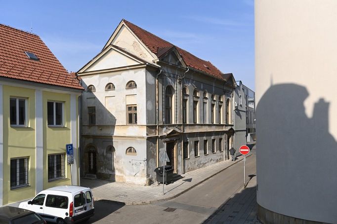 Bývalá synagoga Bet ha-midraš (vlevo za nárožním domem) v Demelově ulici, 10. února 2023, Prostějov. Od roku 2013 je synagoga v seznamu ohrožených památkových objektů.