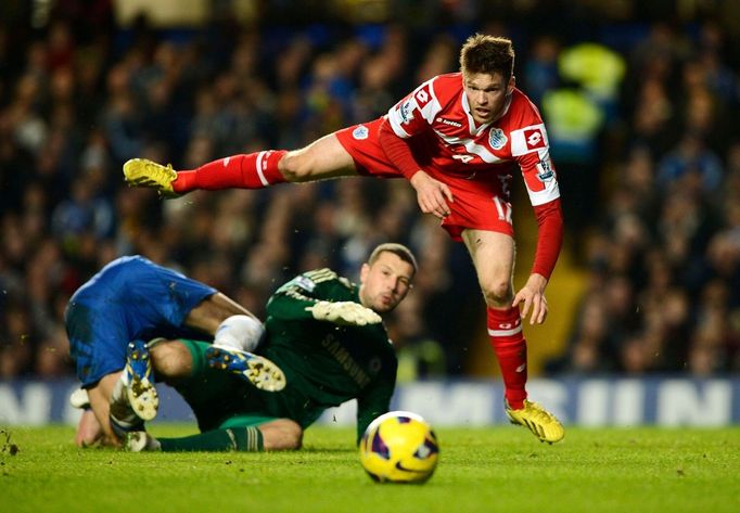 Obránce Chelsea Gary Cahill (v červeném) a gólman  Ross Turnbull se snaží zastavit Jamie Mackie z QPR (vpravo)