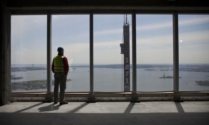 A construction worker looks out the windows of the 71st floor of One World Trade Center as a beam is lifted up by a cable in New York April 30, 2012. The One World Trade Center, built on the Ground Zero site of the fallen World Trade Center Towers, which were brought down in the September 11, 2001 terror attacks, officially surpassed the Empire State Building as the tallest building in New York on Monday. The One World Trade Center will stand at 1,776 feet (541 meters) to the tip of its antenna when it is completed, possibly by late 2013. It will then be the tallest building in the Western Hemisphere and the third tallest building in the world. REUTERS/Andrew Burton (UNITED STATES - Tags: SOCIETY BUSINESS CONSTRUCTION REAL ESTATE CITYSPACE) Published: Dub. 30, 2012, 8:26 odp.