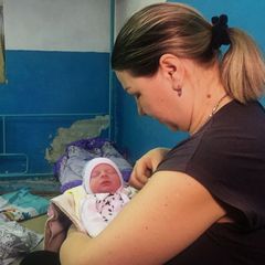 A woman holds her newborn baby as they take shelter in the basement of a perinatal centre in Kharkiv