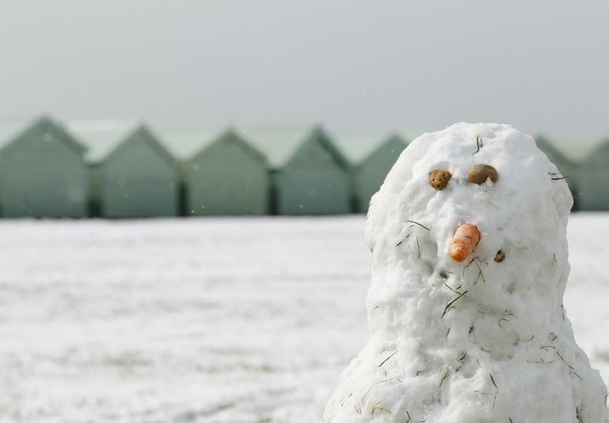 A snowman stands near beach huts in Brighton, southern England March 12, 2013. Southern England was hit with heavy snow overnight. REUTERS/Luke MacGregor (BRITAIN - Tags: ENVIRONMENT SOCIETY) Published: Bře. 12, 2013, 1:12 odp.