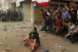 Policisté pozorují příznivce opozice jak protestují proti vládě krále v Káthmándů.