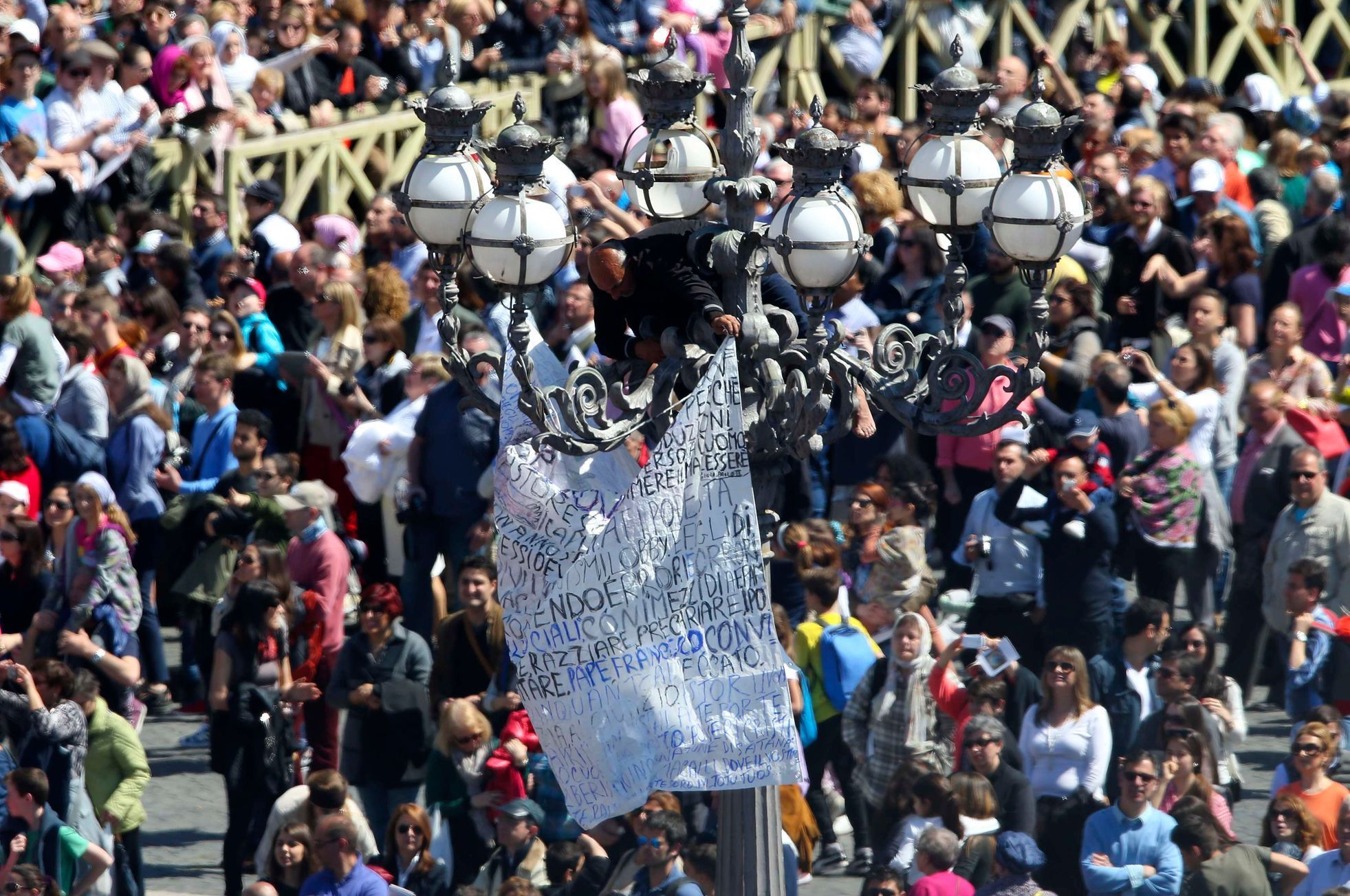 A protester hangs a banner over a street light as Pope Francis leads the Easter Mass in Saint Peter's Square at the Vatican
