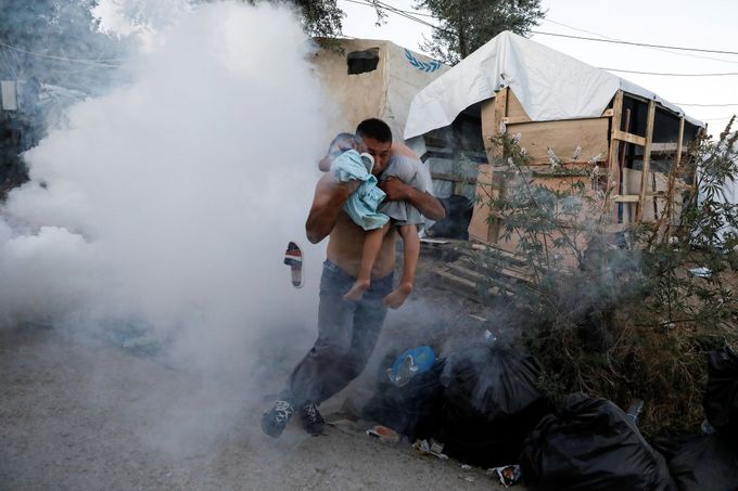 Muž s dítětem prchá před slzným plynem, který v neděli na demonstranty použila policie.