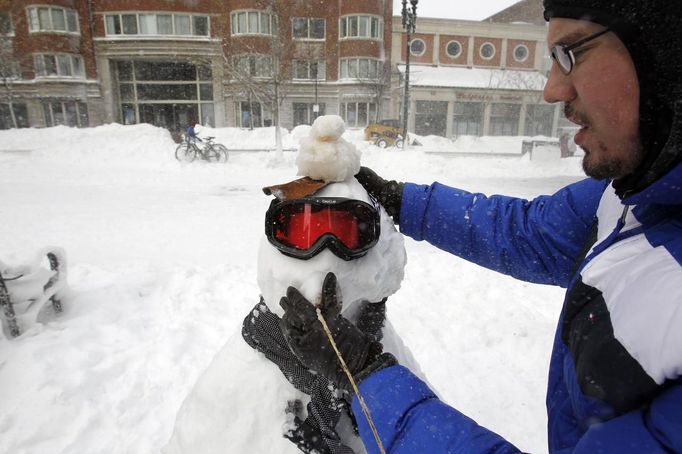 Rafael Coitonho makes a snowman along Boylston Street during a blizzard in Boston, Massachusetts February 9, 2013. REUTERS/Jessica Rinaldi (UNITED STATES - Tags: ENVIRONMENT) Published: Úno. 9, 2013, 7:16 odp.