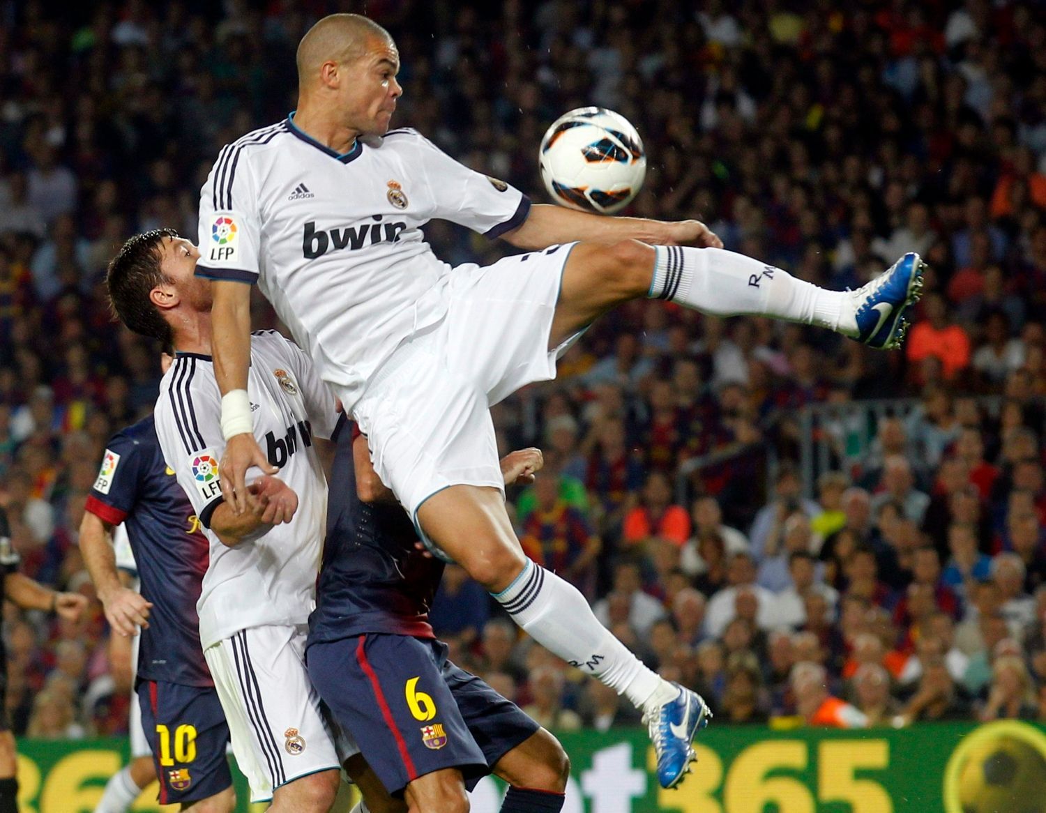 Fotbalista Realu Madrid Pepé (vpravo) skáče pro míč nad spoluhráče Xabi Alonsa v utkání Primera División proti Barceloně.