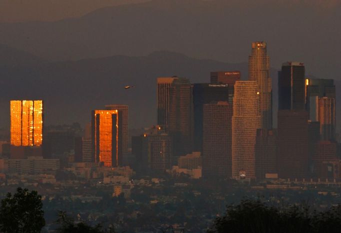 The sun reflects on downtown skyscrapers as it sets through the Los Angeles smog and haze in this October 22, 2006 file photo. California is set to unveil a new weapon in its fight against global climate change November 14, 2012 when it holds its first sale of carbon emissions permits - a landmark experiment that it hopes will serve as a model for other U.S. states and the federal government. REUTERS/Lucy Nicholson/Files (UNITED STATES - Tags: CITYSPACE ENVIRONMENT TRAVEL) Published: Lis. 14, 2012, 5:43 odp.