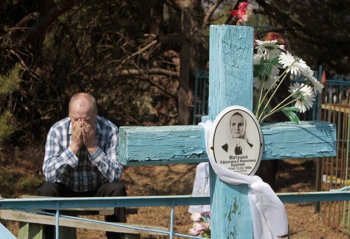 Belarussian man sits at his relative's grave on the eve of Radunitsa in the abandoned village of Tulgovichi