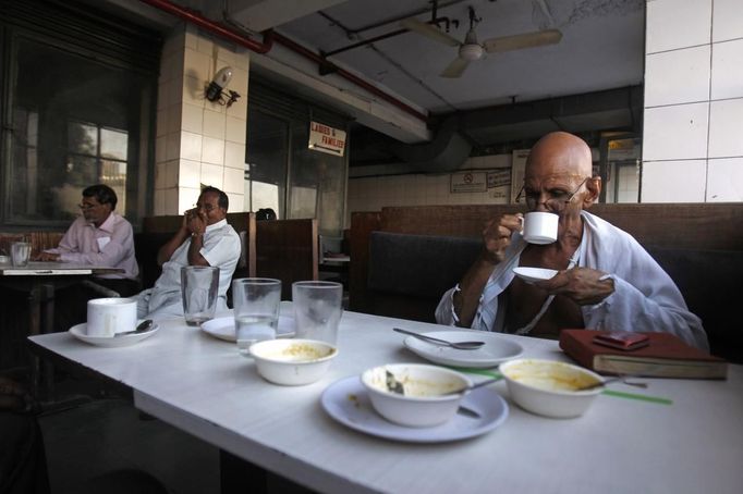 Mahesh Chaturvedi (R), 63, who dresses up like Mahatma Gandhi, drinks coffee inside a restaurant in New Delhi September 28, 2012. Chaturvedi says that the soul of Gandhi resides in him and he has been sent to continue the work of Father of the Nation. After his self proclaimed transformation in 2002 as Gandhi, Chaturvedi has been travelling extensively and plays up to his startling resemblance to Gandhi at protests and demonstrations. Picture taken September 28, 2012. REUTERS/Mansi Thapliyal (INDIA - Tags: SOCIETY) Published: Lis. 26, 2012, 3:58 dop.