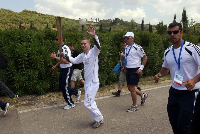 Alexander Loukos, British boxer of Greek descent, waves as he runs with the Olympic flame during the Olympic torch relay at the site of ancient Olympia in Greece May 10, 2012. REUTERS/John Kolesidis (GREECE - Tags: SPORT OLYMPICS) Published: Kvě. 10, 2012, 9:59 dop.