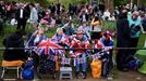 Lidé čekají podél londýnské třídy The Mall, kudy pojedou před polednem král Karel III. s královnou chotí Camillou z Buckinghamského paláce do Westminsterského opatství.