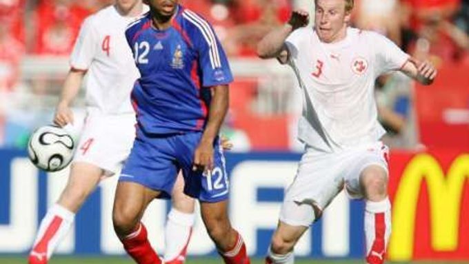 Francouz Thierry Henry (uprostřed) se snaží rozehrát. Za ním dobíhá švýcarský fotbalista Ludovic Magnin.