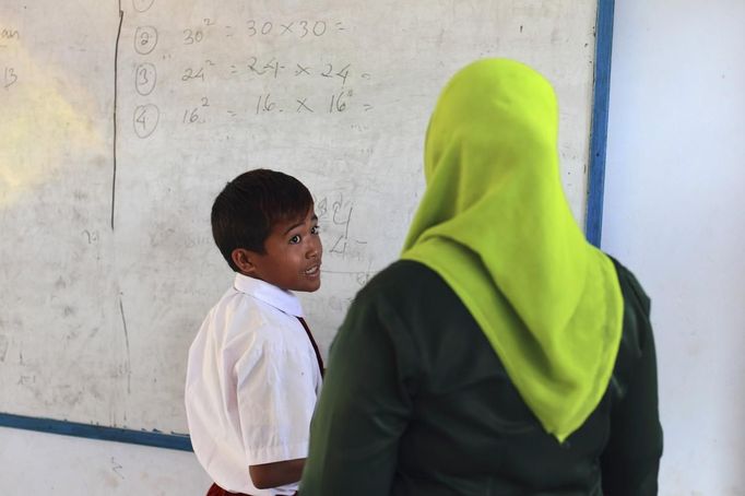 Endiansyah Mohammad (L) talks to his teacher during class in Dompu, November 20, 2012. Dozens of child jockeys, some as young as eight-years-old take part in the races. Involving nearly 600 horses they take place around a dusty, oval track of 1,400 meters (nearly one mile). The reward, for the winner is a handful of cash for his family, and glory for the jockey. The grand prize is one million rupiah ($100). Those who win their groups get two cows. The chairman of the races' organising team, Hajji Sukri, denies that there is any danger to the children saying they are all skilful riders and none has been killed or seriously hurt. Picture taken November 20, 2012. REUTERS/Beawiharta (INDONESIA - Tags: SPORT SOCIETY) ATTENTION EDITORS: PICTURE 23 of 25 FOR PACKAGE 'BETTING ON CHILD JOCKEYS' Published: Lis. 24, 2012, 9:17 dop.