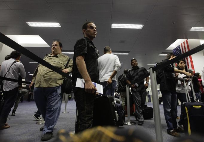 Luis Salgado, nicknamed Chucho, holds his passport as he waits in line at U.S. Immigration, upon arriving at Miami airport on a direct flight from Havana, March 13, 2013. Chucho was granted a U.S. visa based on his father's status as legal resident in Texas, and he was reunited in Miami with his father, Jesus Salgado, who had escaped Cuba on a frail boat ten years earlier. The Salgados are among many Cubans taking advantage of Cuba's new travel policy in place since last January, which allows citizens to leave the country with just a passport and no need for much-hated exit visas required since 1961. Picture taken March 13, 2013. REUTERS/Desmond Boylan (UNITED STATES - Tags: POLITICS SOCIETY) Published: Dub. 11, 2013, 1:21 odp.