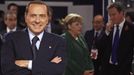 Berlusconi pózuje před fotoaparáty, zatímco německá kancléřka Angela Merkelová se v pozadí baví s britským premiérem Davidem Cameronem na summitu zemí skupiny G20 v Cannes - 3. listopadu 2011.