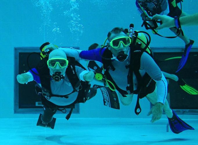 French athlete Philippe Croizon (L), whose arms and legs were amputated after an electric shock accident in March 1994, swims next to an unidentified diver in a 33 metre (36 yard) deep pool, the world's deepest pool built to train professional divers, at Nemo33 diving centre in Brussels January 10, 2013. Croizon, who swam with adapted prostheses that had fins attached, broke a world record and became the first disabled person to dive to 33 metres, according to the organisers. REUTERS/Yves Herman (BELGIUM - Tags: SOCIETY SPORT DIVING) Published: Led. 10, 2013, 4:39 odp.