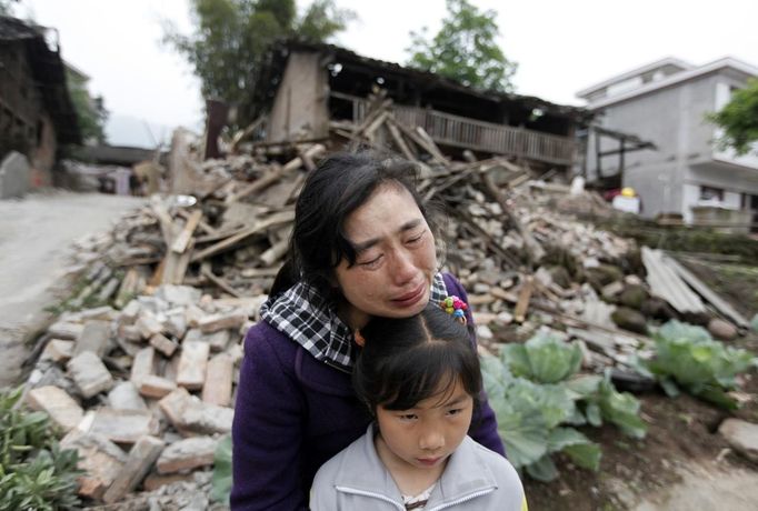 Song Zhengqiong, holding her daughter, cries in front of her damaged house after a strong 6.6 magnitude earthquake at Longmen village, Lushan county in Ya'an, Sichuan province April 21, 2013. Rescuers poured into a remote corner of southwestern China on Sunday as the death toll from the country's worst earthquake in three years climbed to 164 with more than 6,700 injured, state media said. REUTERS/Jason Lee (CHINA - Tags: DISASTER ENVIRONMENT TPX IMAGES OF THE DAY) Published: Dub. 21, 2013, 4:18 dop.