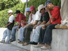 Stavební dělníci čekají v Miami, zda si je někdo najme na práci.