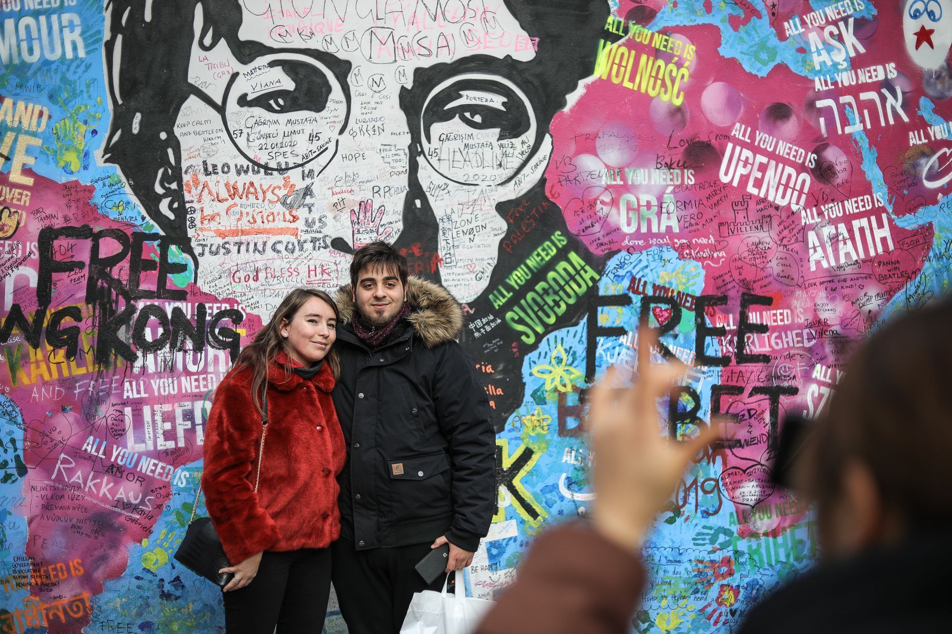 Lennonova zeď po třech měsících od malování - turisté, graffiti