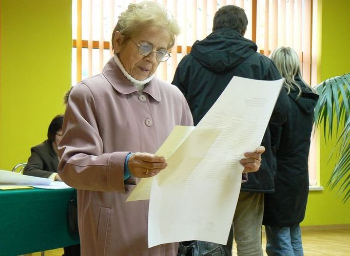 Žena odchází s archem ve volební místnosti ve Vadovicích.