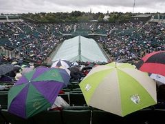 Diváci na centrálním kurtu Wimbledonu se musí schovávat pod deštníky, i v sobotu narušil program déšť.