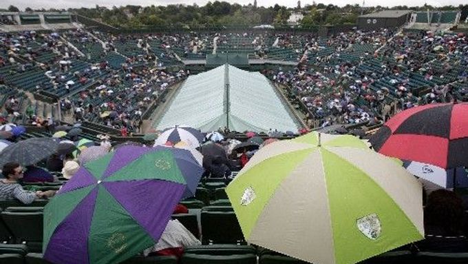 Diváci na centrálním kurtu Wimbledonu se musí schovávat pod deštníky, i v sobotu narušil program déšť.