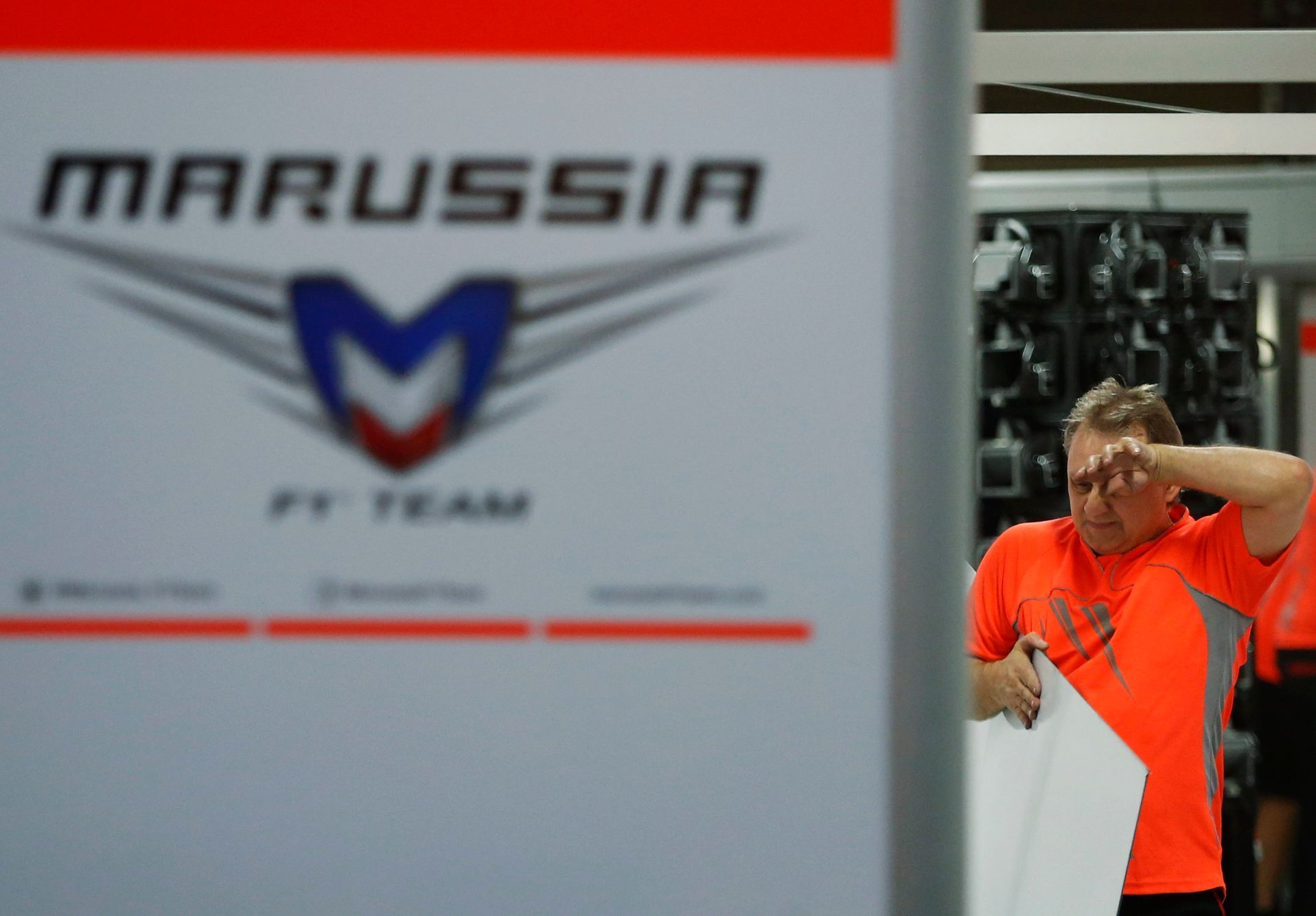 A pit crew of Marussia, which Formula One driver Jules Bianchi of France belongs to, wipes his face as he cleans up the pit after the Japanese F1 Grand Prix at the Suzuka Circuit