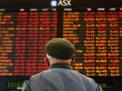 Muž sleduje panel s vývojem akcií na burze v australském Melbourne
