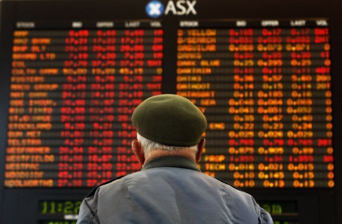 Muž sleduje panel s vývojem akcií na burze v australském Melbourne