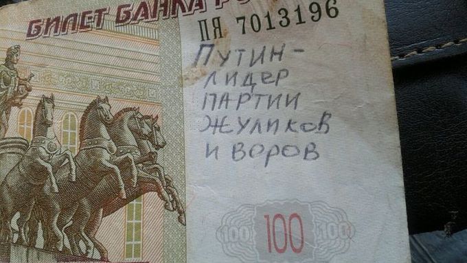 Rusové popisují bankovky nadávkami na Putina. Na téhle stojí: "Putin je šéf partaje podvodníků a zlodějů."