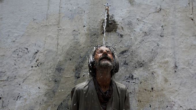 Muž se ochlazuje z veřejného vodovodu během vlny veder v Karáčí