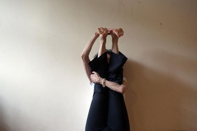 Yoga instructor Tao Porchon-Lynch helps a student through a yoga hand stand in her yoga class in Hartsdale, New York, May 14, 2012. At 93 years old, Porchon-Lynch was named the world's oldest yoga teacher by Guinness World Records. REUTERS/Keith Bedford (UNITED STATES - Tags: SOCIETY) Published: Kvě. 14, 2012, 10:49 odp.