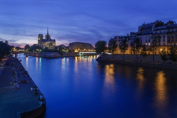 Lidé na březích Seiny s katedrálou Notre-Dame na ostrově Île de la Cité, Paříž, Francie, 8. srpna 2012.