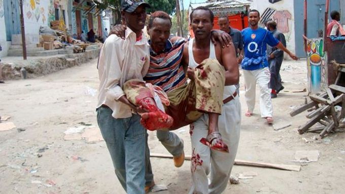Somálští muži přenášejí zraněného po útoku na tržiště Bakara v Mogadišu