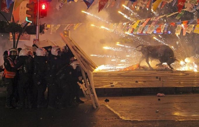 Pořádková policie se kryje před vybuchujícími dělobuchy házenými demonstranty během protivládních demonstrací v istanbulské čtvrti Kadikoy, 11. března 2014.