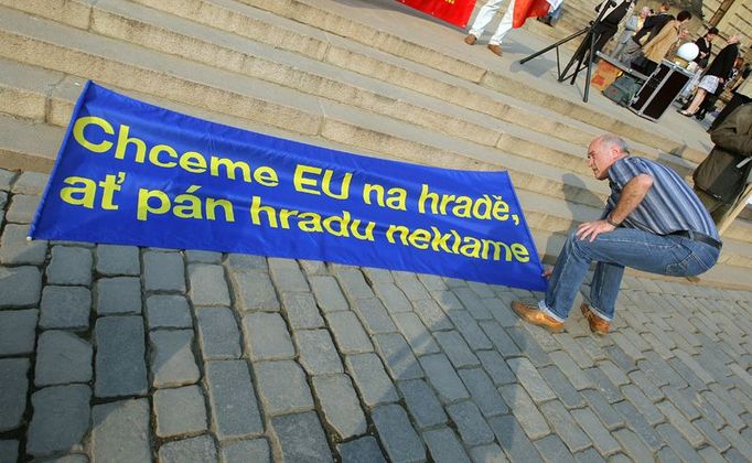 Svolavatel demonstrace Jan Šinágl rozvíjí transparent na schodech před Rudolfinem.