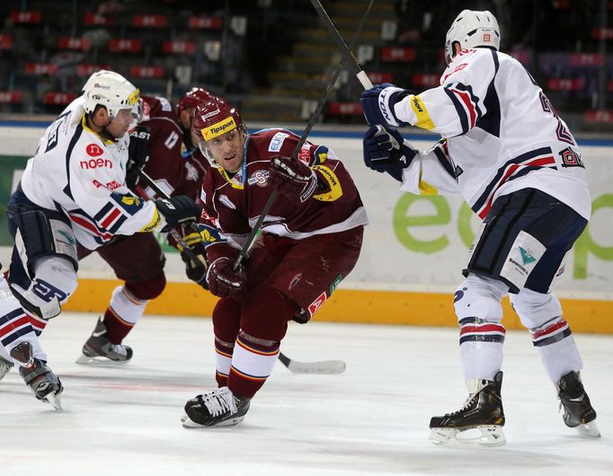 Hokejisté Chomutova Jaroslav Mrázek (vlevo) a Brett Palin brání Tomáše Rachůnka v utkání 16. kola Tipsport extraligy 2012/13 proti Spartě Praha.