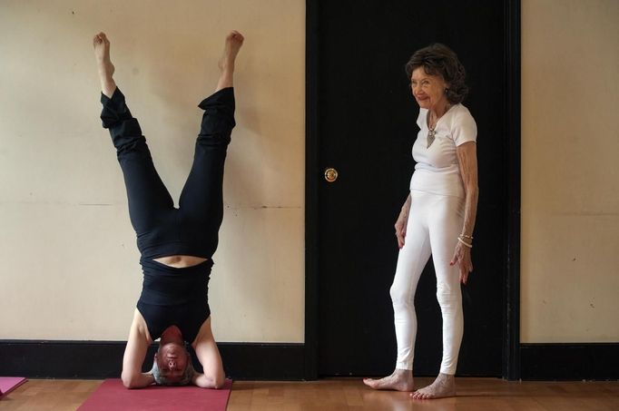 Yoga instructor Tao Porchon-Lynch helps a student through a yoga hand stand in her yoga class in Hartsdale, New York, May 14, 2012. At 93 years old, Porchon-Lynch was named the world's oldest yoga teacher by Guinness World Records. REUTERS/Keith Bedford (UNITED STATES - Tags: SOCIETY) Published: Kvě. 14, 2012, 10:48 odp.