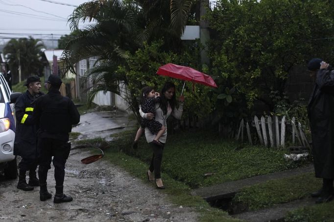 A woman carries a child while walking near police officers after a shoot-out between gang members of the Mara 18 street gang and police and military during an anti-drug operation in San Pedro Sula March 27, 2013. San Pedro Sula, the country's second largest city after Tegucigalpa, has a homicide rate of 169 per 100,000 people and was named the world's most violent city for a second year in a row. Lax laws allow civilians to own up to five personal guns. Arms trafficking has flooded the country with nearly 70% illegal firearms. 83.4% of homicides are by firearms, compared to 60% in the United States. Picture taken March 27, 2013. REUTERS/Jorge Cabrera (HONDURAS - Tags: CRIME LAW CIVIL UNREST HEALTH) ATTENTION EDITORS: PICTURE 10 OF 39 FOR PACKAGE 'GUN CULTURE - HONDURAS' SEARCH 'HONDURAS GUN' FOR ALL IMAGES Published: Dub. 5, 2013, 11:14 dop.